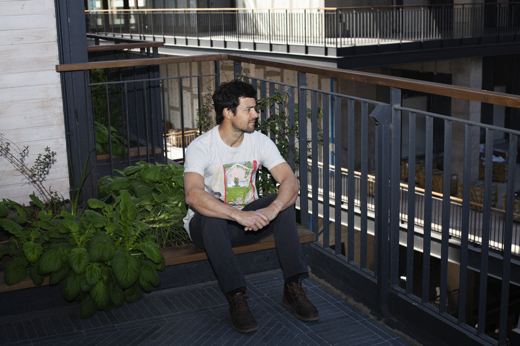 Modelo con polera de arte BIG PINK de Sergio Coddou. Versión color Dust, Classic Fit. Foto de estilo urbano. De perfil.